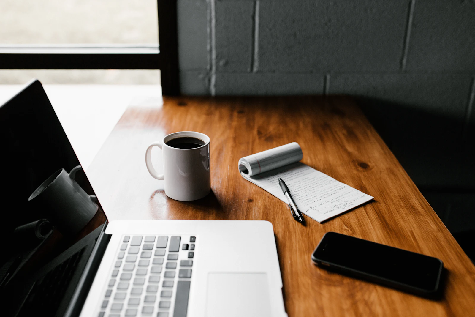 Laptop, coffee and a notepad on a desk — making a quotation online
